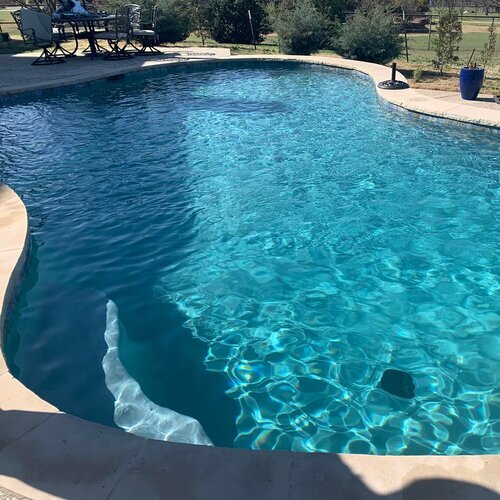 freeform pool surrounded by patio furniture