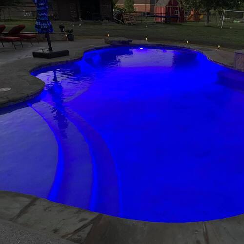 freeform pool at nighttime with lighting